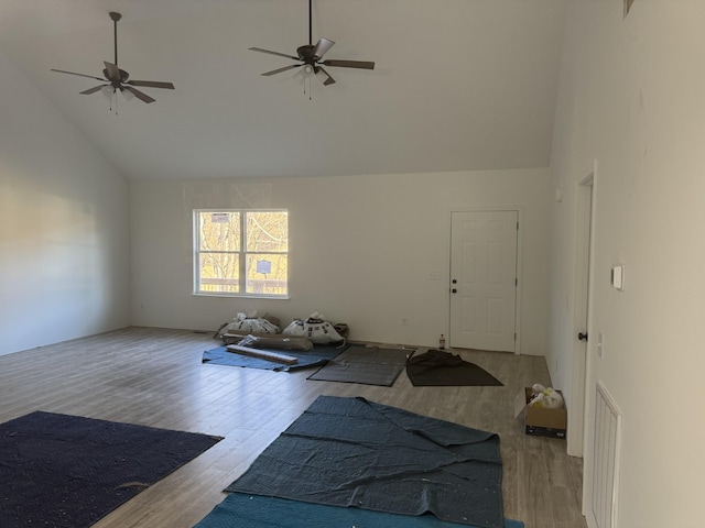 exercise area featuring ceiling fan, high vaulted ceiling, and light wood-type flooring