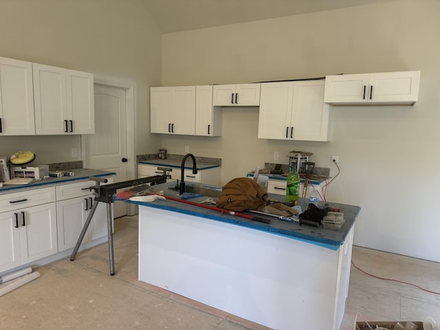 kitchen with white cabinets, a center island, sink, and vaulted ceiling