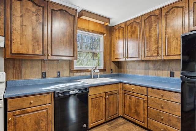 kitchen with sink, wood-type flooring, black appliances, and wooden walls