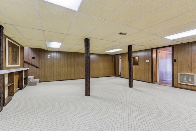 basement featuring a drop ceiling, heating unit, and light colored carpet