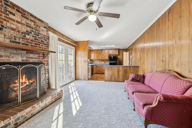 living room featuring crown molding, ceiling fan, a brick fireplace, light colored carpet, and wood walls