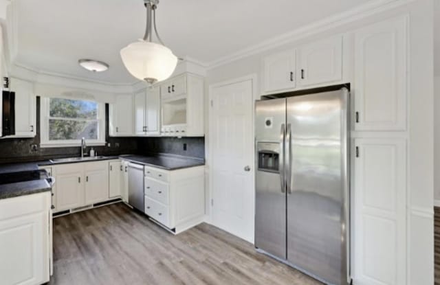 kitchen with white cabinets, appliances with stainless steel finishes, sink, and pendant lighting