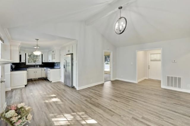 kitchen featuring white cabinetry, beamed ceiling, decorative light fixtures, and stainless steel refrigerator with ice dispenser