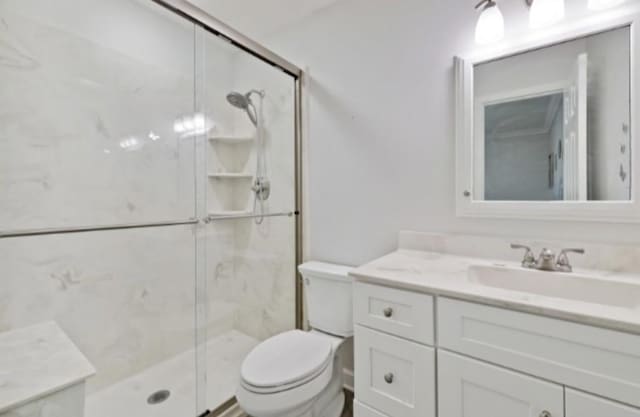 bathroom with toilet, an enclosed shower, and vanity