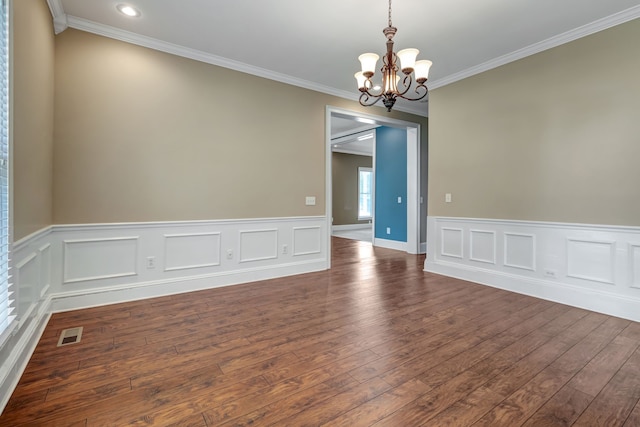 spare room with ornamental molding, an inviting chandelier, and dark hardwood / wood-style floors