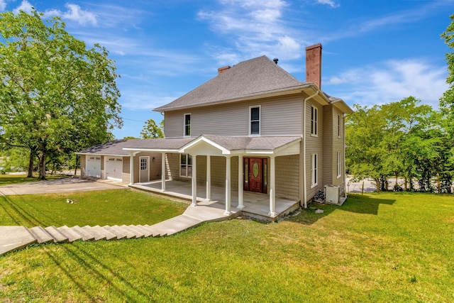 rear view of property with a garage and a lawn