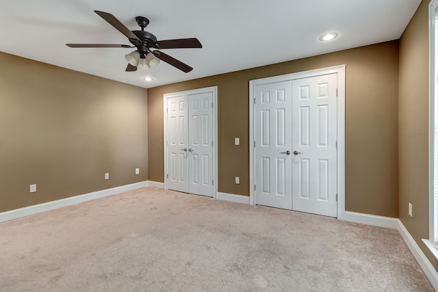 unfurnished bedroom featuring multiple closets, carpet flooring, and ceiling fan