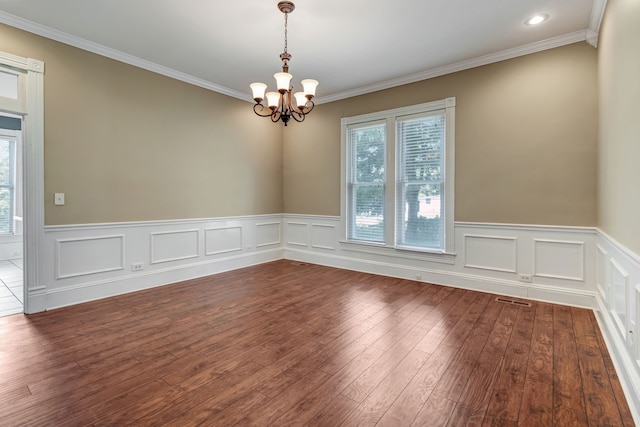 empty room with dark wood-type flooring, a chandelier, and ornamental molding