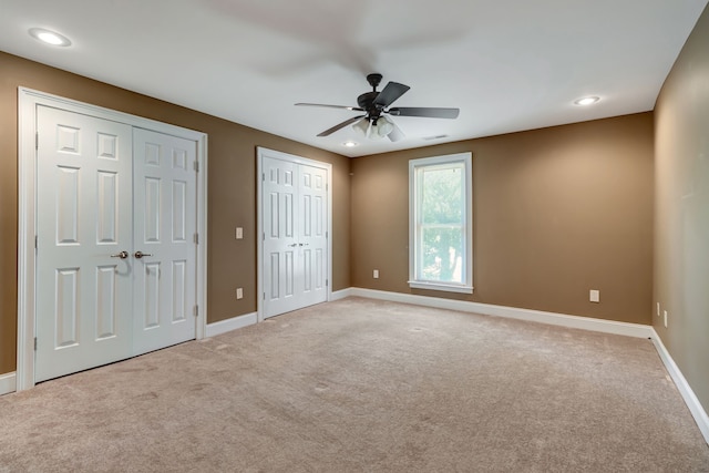 unfurnished bedroom with multiple closets, carpet floors, and ceiling fan