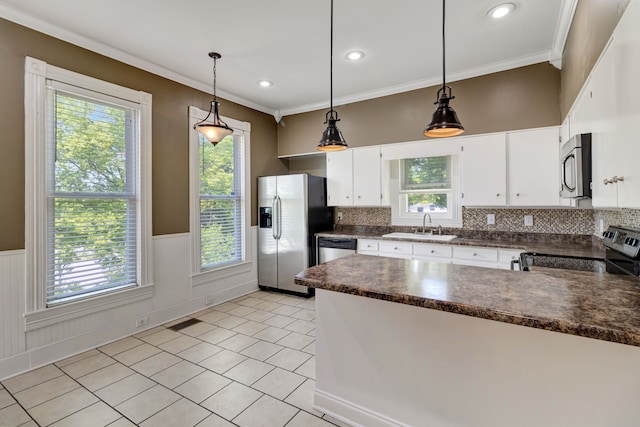 kitchen with hanging light fixtures, appliances with stainless steel finishes, white cabinets, and decorative backsplash