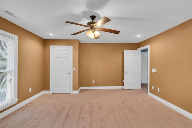 unfurnished bedroom with light carpet, multiple windows, and ceiling fan