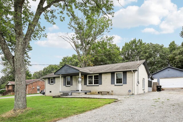 single story home featuring a garage, a front lawn, and an outbuilding