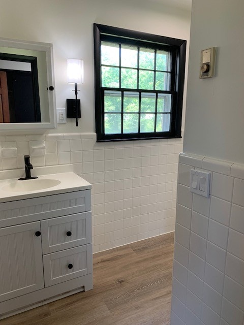 bathroom with hardwood / wood-style flooring, vanity, and tile walls