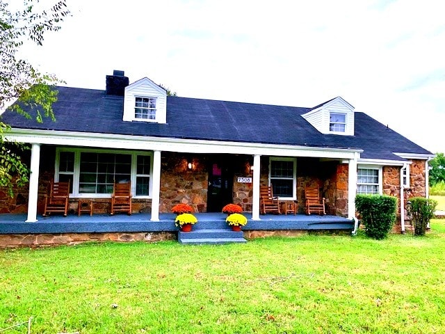 rear view of property with covered porch and a yard