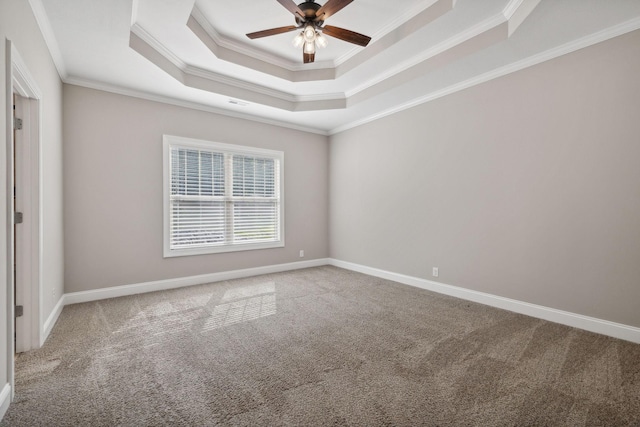 carpeted spare room with a raised ceiling, ornamental molding, and ceiling fan