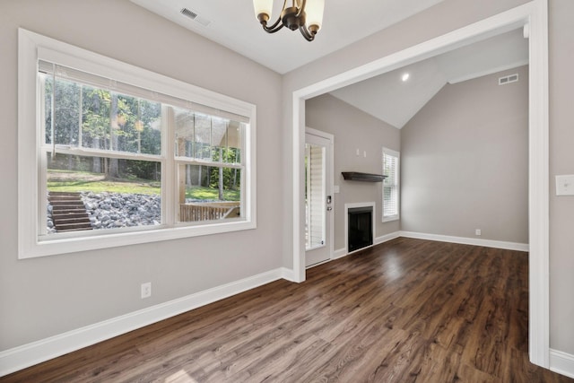 unfurnished living room featuring dark hardwood / wood-style flooring, a notable chandelier, vaulted ceiling, and a healthy amount of sunlight