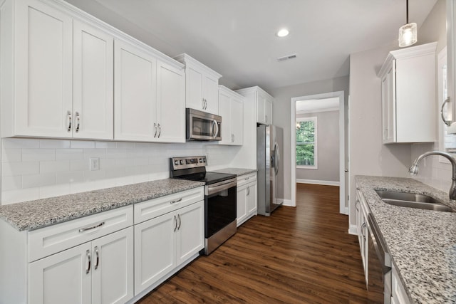 kitchen with stainless steel appliances, sink, pendant lighting, and white cabinets