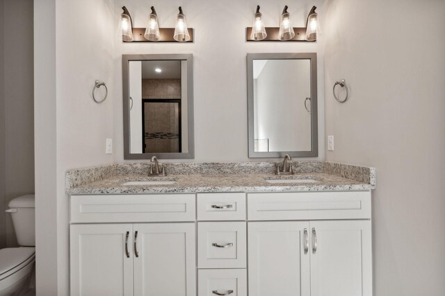 bathroom with dual vanity and toilet