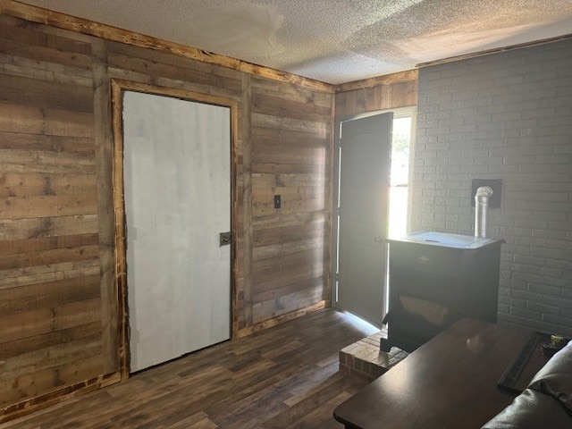 interior space with dark hardwood / wood-style flooring, a textured ceiling, and wooden walls