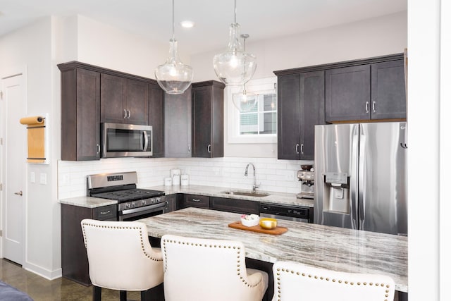 kitchen with sink, a kitchen breakfast bar, hanging light fixtures, light stone counters, and stainless steel appliances