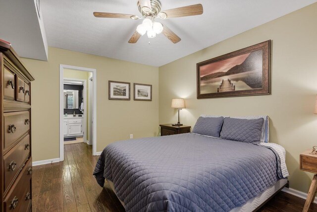 bedroom with dark wood-type flooring, ceiling fan, sink, and ensuite bath