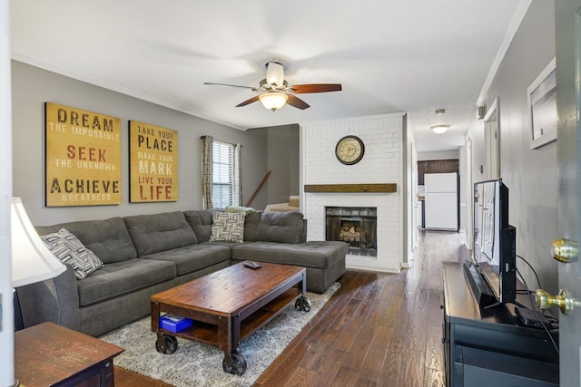 living room featuring dark wood-type flooring, ceiling fan, ornamental molding, and a fireplace