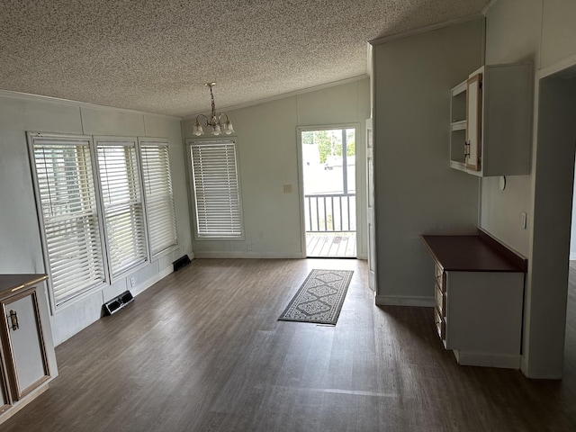 unfurnished dining area featuring dark hardwood / wood-style flooring, ornamental molding, a textured ceiling, an inviting chandelier, and lofted ceiling