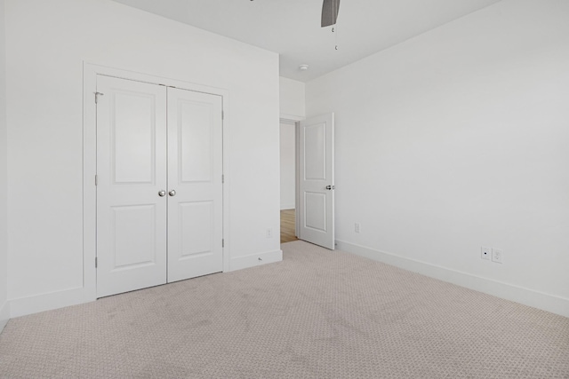 unfurnished bedroom featuring ceiling fan, light colored carpet, and a closet