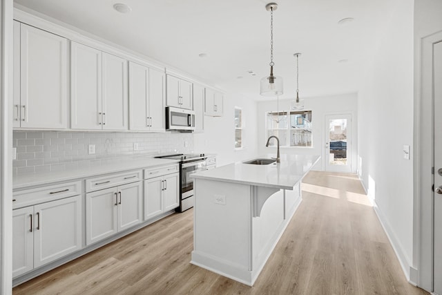 kitchen with pendant lighting, sink, stainless steel appliances, and white cabinets