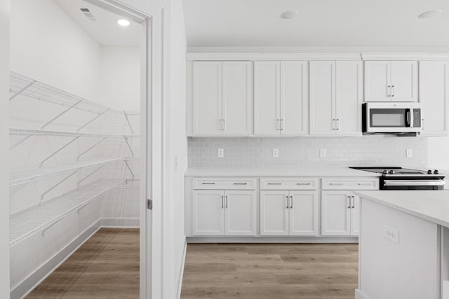 kitchen with decorative backsplash, appliances with stainless steel finishes, light hardwood / wood-style flooring, and white cabinets