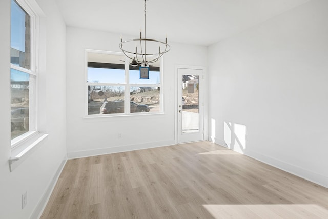 unfurnished dining area with plenty of natural light, a chandelier, and light wood-type flooring