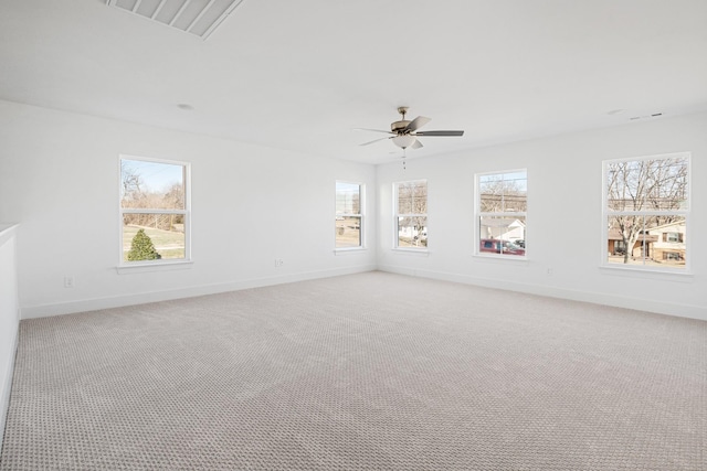 empty room featuring ceiling fan, light colored carpet, and a healthy amount of sunlight