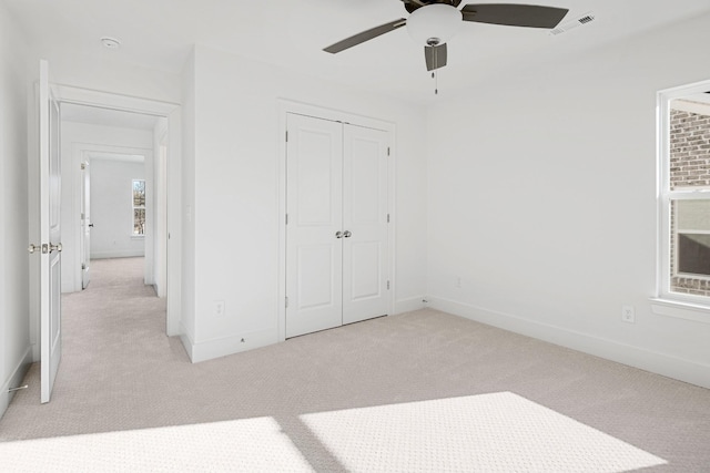 unfurnished bedroom featuring light colored carpet, ceiling fan, and a closet