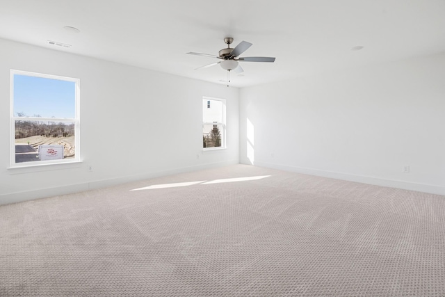 unfurnished room featuring plenty of natural light, ceiling fan, and carpet