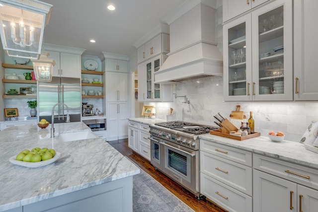 kitchen featuring decorative light fixtures, white cabinets, premium appliances, light stone counters, and custom range hood