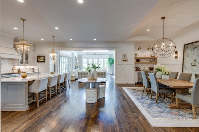 dining space featuring dark wood-type flooring, ornamental molding, and a notable chandelier