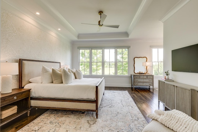 bedroom featuring dark wood-type flooring, ceiling fan, ornamental molding, and a tray ceiling