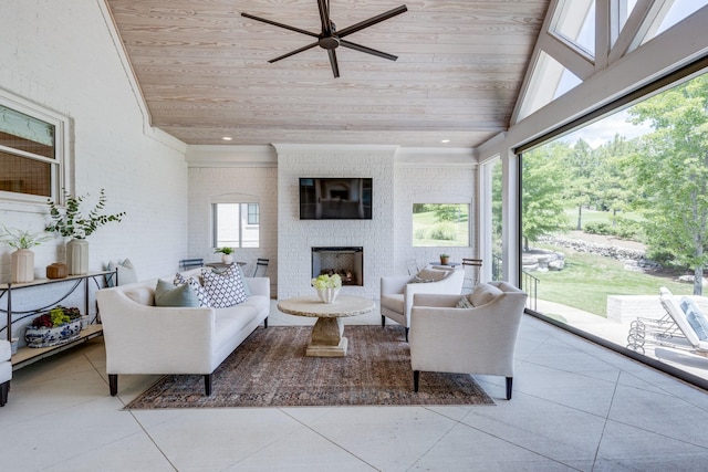 sunroom / solarium featuring wood ceiling, a large fireplace, ceiling fan, and vaulted ceiling