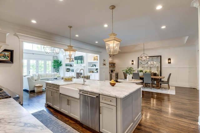 kitchen featuring pendant lighting, an island with sink, sink, stainless steel dishwasher, and light stone counters