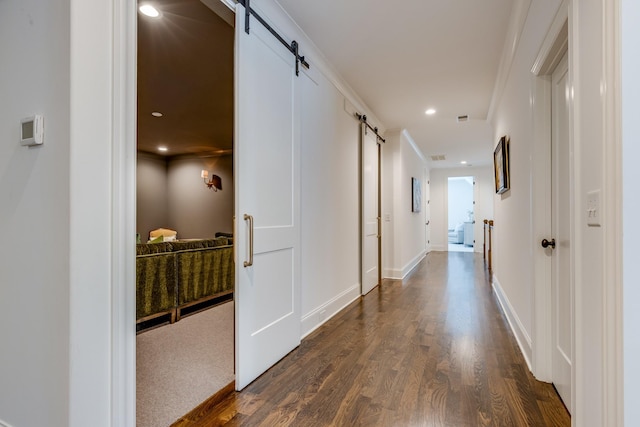 hallway featuring dark hardwood / wood-style floors, a barn door, and crown molding