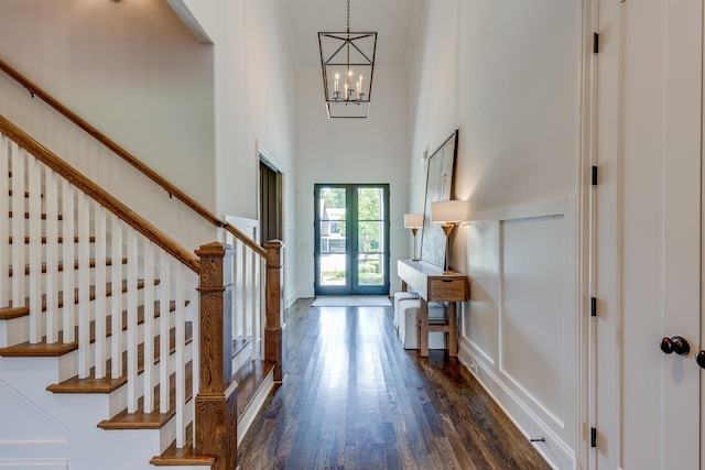 entrance foyer with dark wood-type flooring, a towering ceiling, and a chandelier