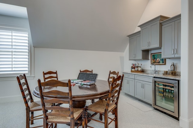 carpeted dining space featuring lofted ceiling, wet bar, and wine cooler