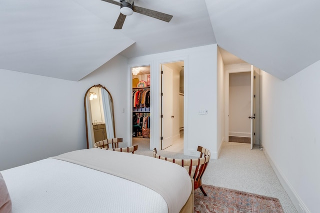 carpeted bedroom featuring ceiling fan, a spacious closet, vaulted ceiling, and a closet