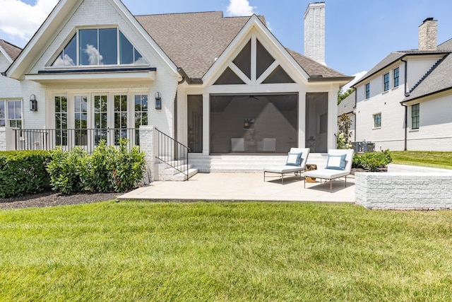 rear view of property featuring a yard, a sunroom, and a patio