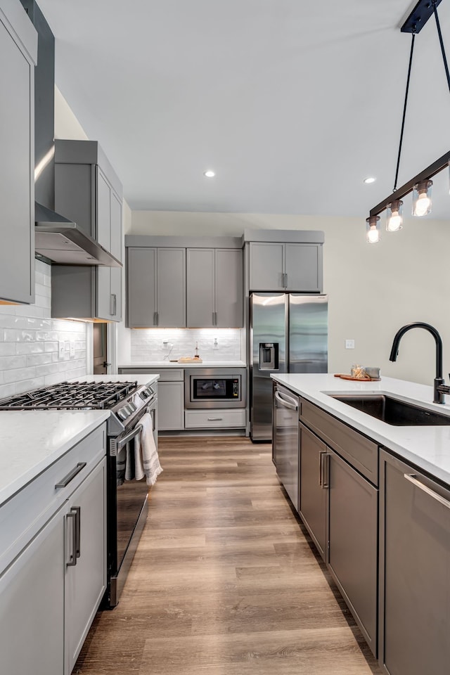 kitchen featuring light hardwood / wood-style floors, sink, decorative backsplash, and appliances with stainless steel finishes