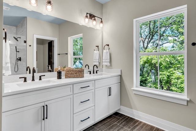 bathroom with dual vanity and a tile shower