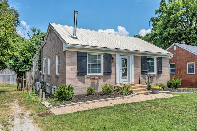 view of front of home featuring a front yard, metal roof, and brick siding