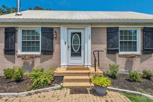 property entrance with metal roof and brick siding