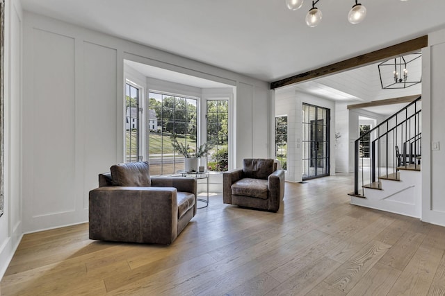 living room with beam ceiling, a chandelier, and light hardwood / wood-style flooring