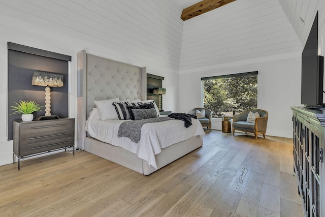 bedroom featuring beamed ceiling, a towering ceiling, and light wood-type flooring